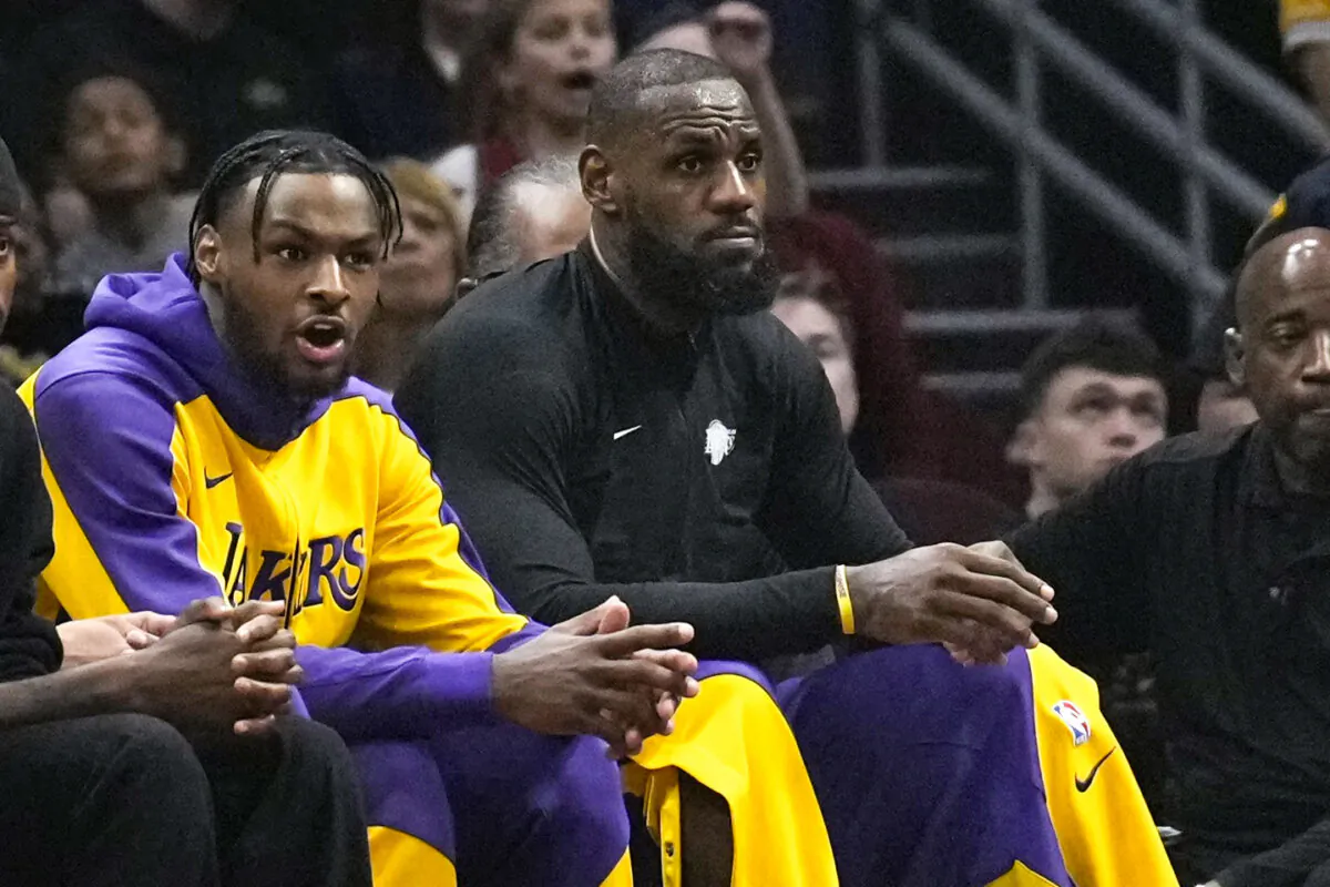 Los Angeles Lakers guard Bronny James (L) and forward LeBron James watch from the bench in the first half of a game against the Cleveland Cavaliers in Cleveland on Oct. 30. (Sue Ogrocki/AP Photo)