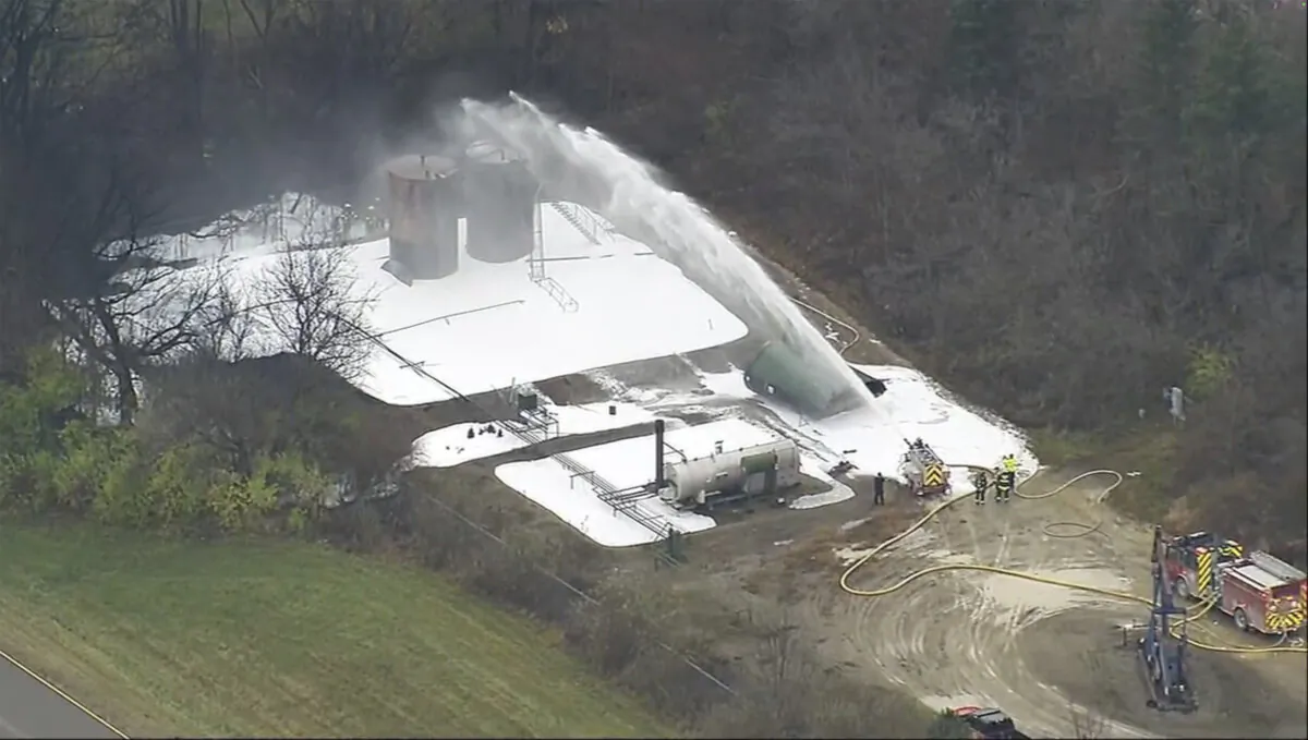 Firefighters work to extinguish a fire after a tank containing byproducts from oil drilling operations exploded near the General Motors Proving Ground in Milford, Mich., on Nov. 26, 2024. (WXYZ via AP)