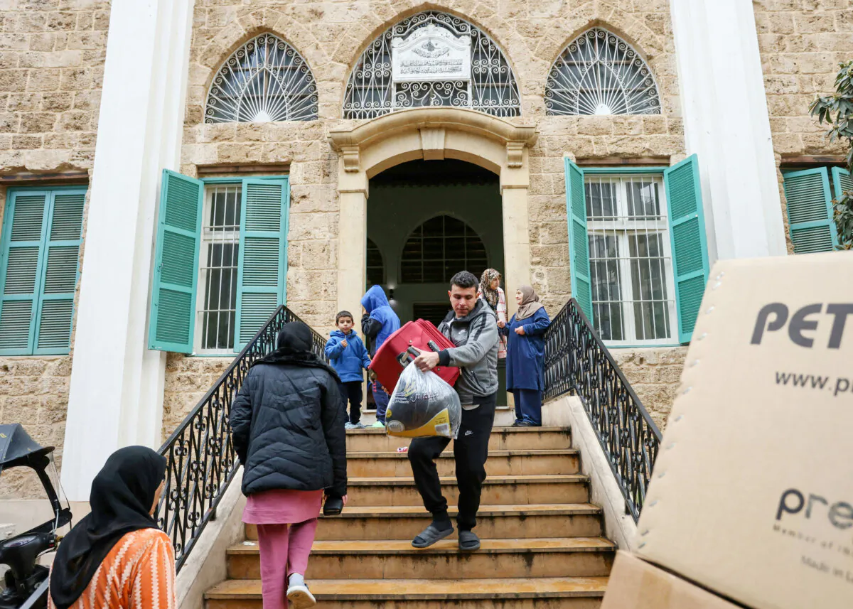 Displaced people carry their belongings as they leave a school turned shelter in Beirut, Lebanon, on Nov. 27, 2024, as people return to their homes after a ceasefire between Israel and Hezbollah took effect. (IBRAHIM AMRO/AFP via Getty Images)