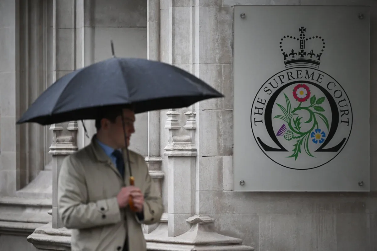 A pedestrian holding an umbrella walks past the Supreme Court in London on Nov. 23, 2022. (Justin Tallis/AFP via Getty Images)