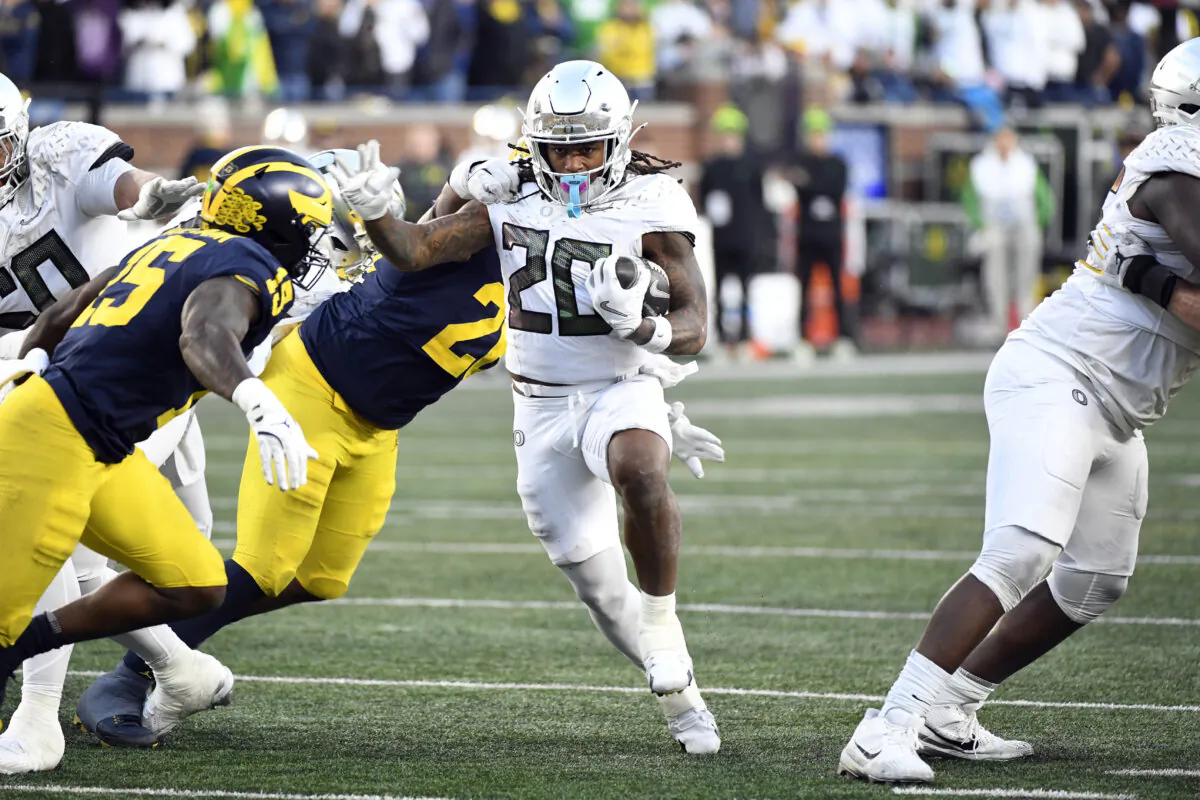 Oregon running back Jordan James (20) runs with the ball and is chased by Michigan linebacker Ernest Hausmann (15) and defensive lineman Rayshaun Benny (26) during the second half of an NCAA college football game in Ann Arbor, Mich., on Nov. 2, 2024. (Jose Juarez/AP Photo)