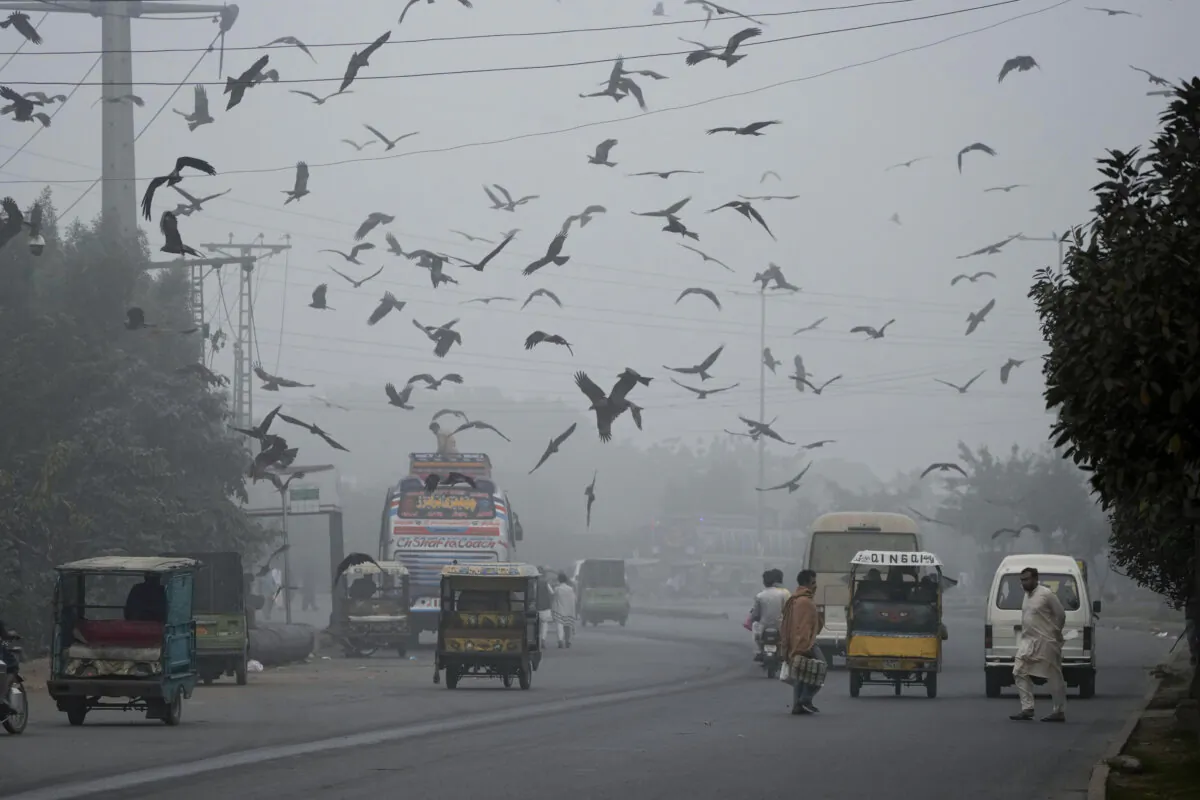 People cross a road as smog envelopes the areas of Lahore, Pakistan, on Nov. 13, 2024. (K.M. Chaudary/AP Photo)