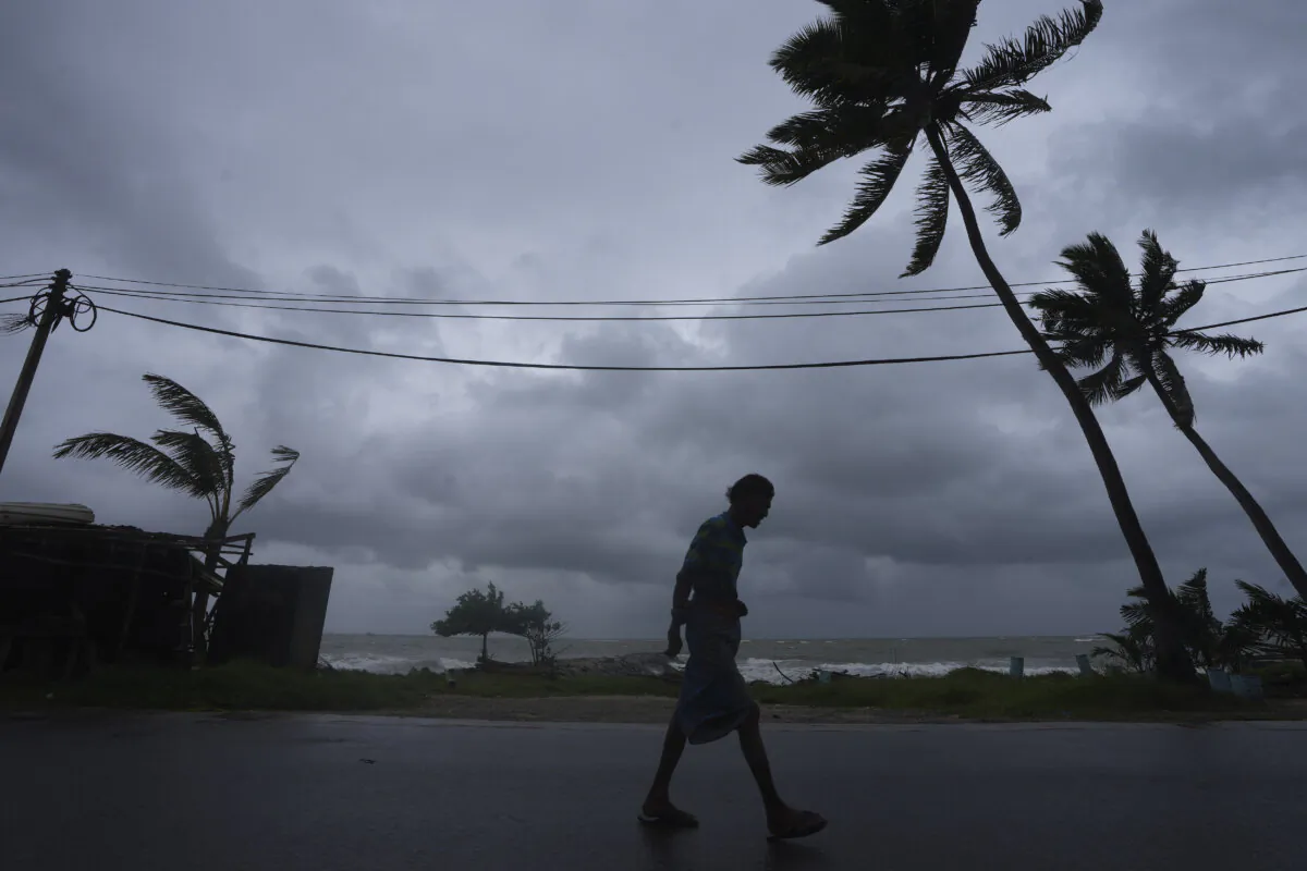 Dark clouds hover as a man walks along a street in Colombo, Sri Lanka, Wednesday, Nov. 27, 2024. (Eranga Jayawardena/AP Photo)