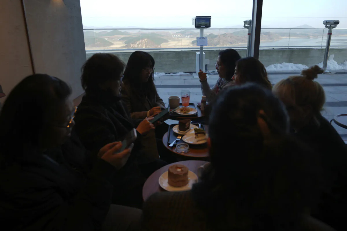 Visitors sit at a newly opened Starbucks store as North Korea's Kaephung county is seen in the background at the observatory of the Aegibong Peace Ecopark in Gimpo, South Korea, on Nov. 29, 2024. (Lee Jin-man/AP Photo)