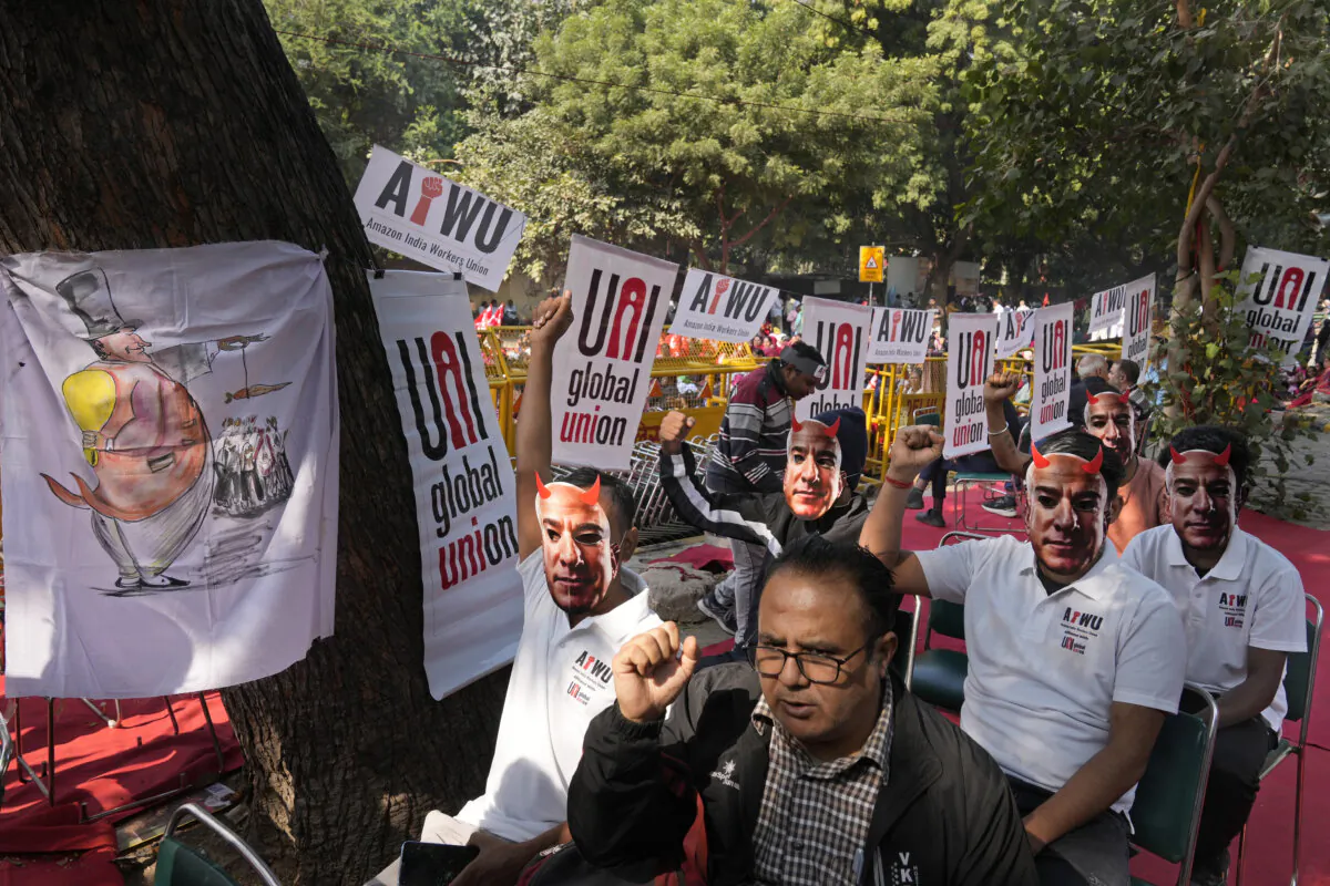 Participants wear paper masks in the likeness of Amazon's Jeff Bezos as warehouse workers and delivery drivers stage a protest against the Seattle-based company demanding higher wages and better working conditions, in New Delhi, India, on Nov. 29, 2024. (Manish Swarup/AP Photo)