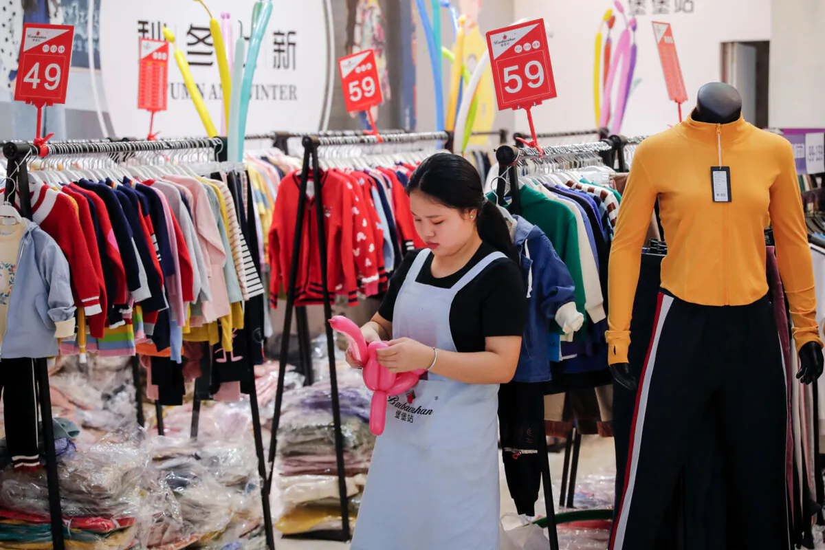 An employee uses balloons to attract customers at a fashion retailer running a promotion sale at a shopping mall in Shenzhen, Guangdong Province, China, on Nov. 1, 2019. (Andy Wong/AP)