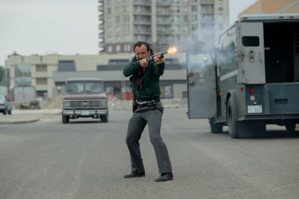 man with shotgun stands near Brinks truck in The Order