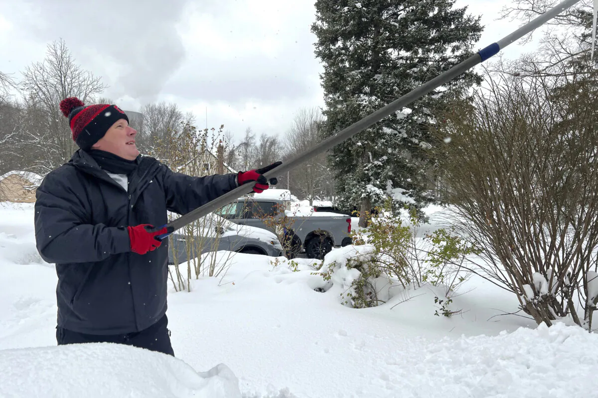 Resident Todd Brainard cleans snow off of the roof of his home in North Perry, Ohio, on Dec. 3, 2024. (Patrick Aftoora-Orsagos/AP Photo)