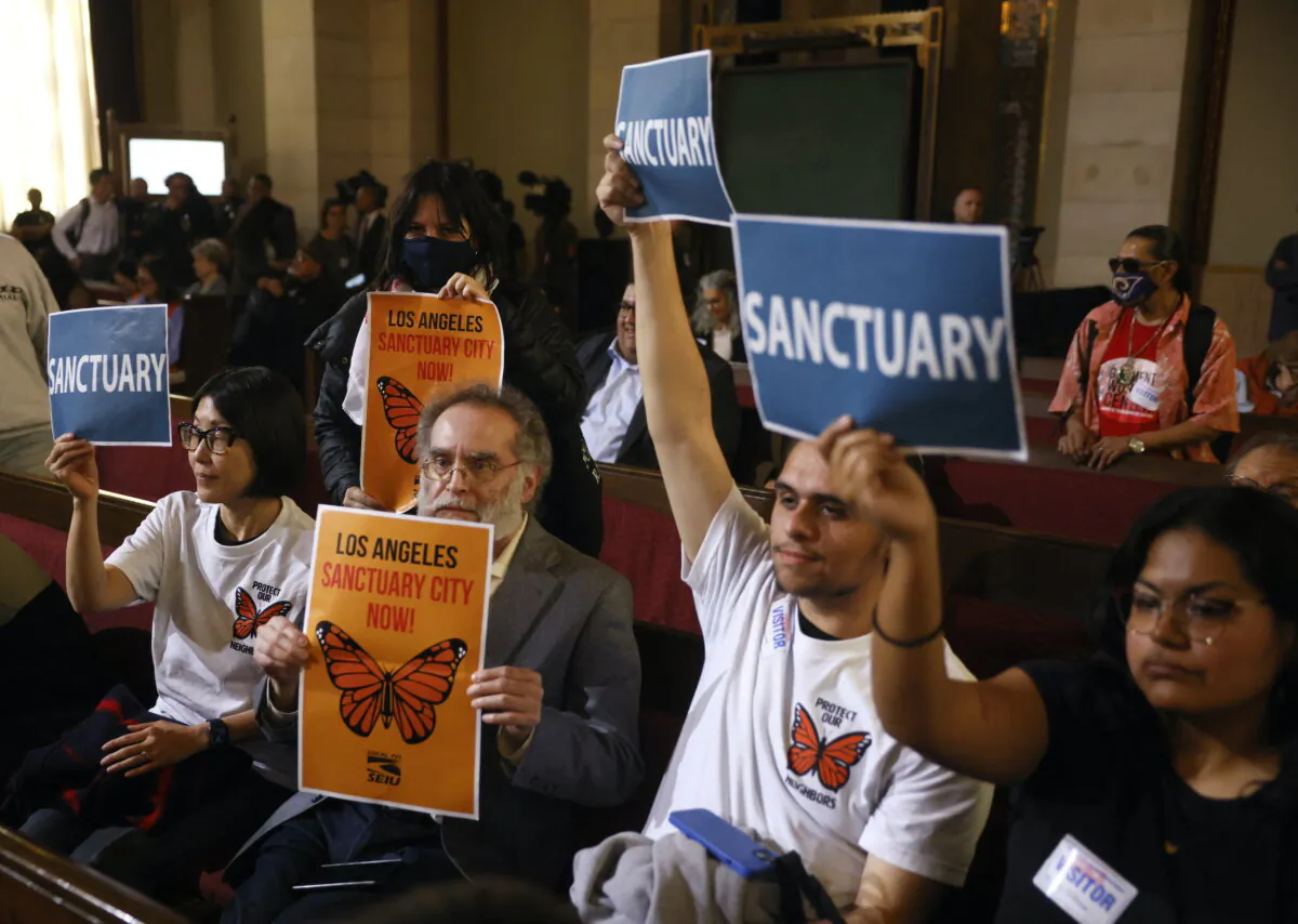 People in the audience hold up signs as the Los Angeles City Council considers a "sanctuary city" ordinance during a meeting at City Hall in Los Angeles on Nov. 19, 2024. (Etienne Laurent/AFP via Getty Images)