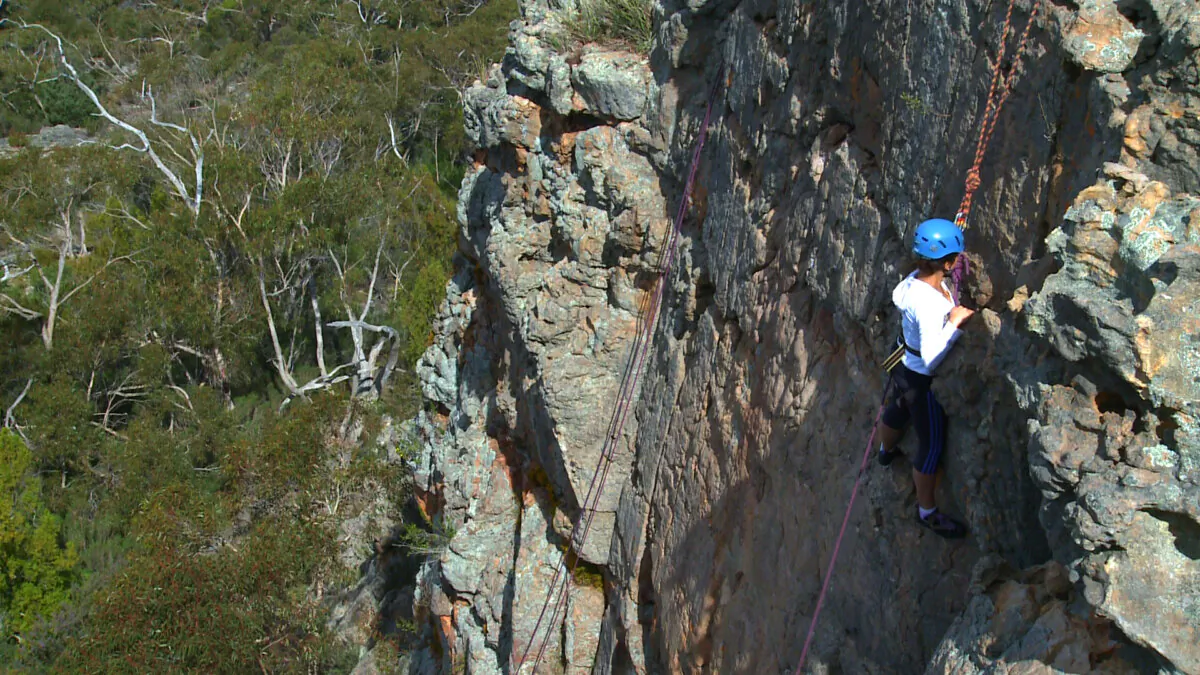 An undated video screenshot of a person scaling a rock face on Mount Arapiles, Victoria in Australia. (AAP Image/Mark Tadic)