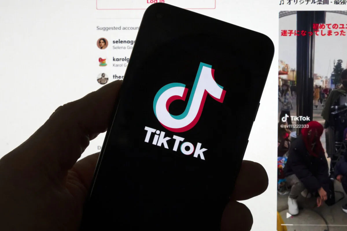 The TikTok logo is displayed on a mobile phone in front of a computer screen that displays a TikTok home page, in Boston, Mass., on March 18, 2023. (Michael Dwyer/AP Photo)