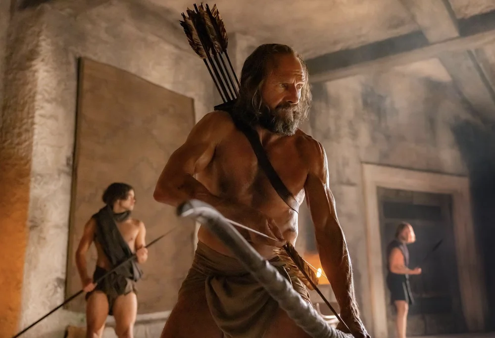 Odysseus (Ralph Fiennes) preparing to shoot an arrow through the holes of 12 lined-up axes, to win back his wife, in "The Return." (Bleecker Street)