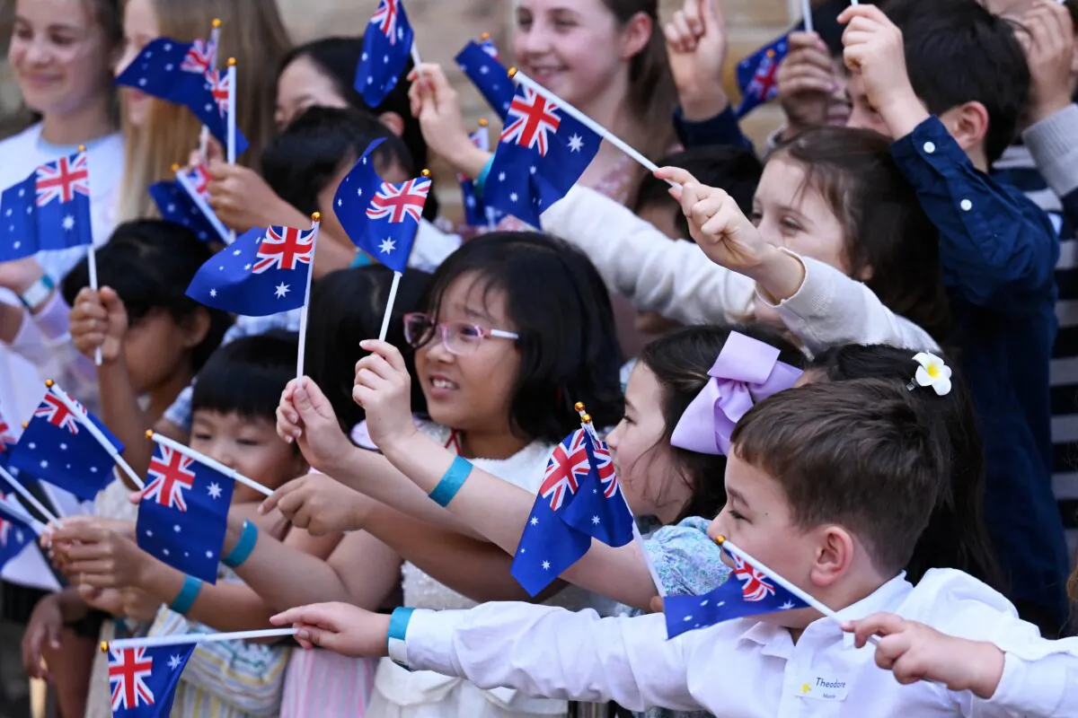 Children wave Australian flags for the arrival of Britain's King Charles III and Queen Camilla to attend a Sunday morning service at St Thomas' Anglican Church in Sydney, Australia on Oct. 20, 2024. (Dean Lewins/Pool/AFP via Getty Images)