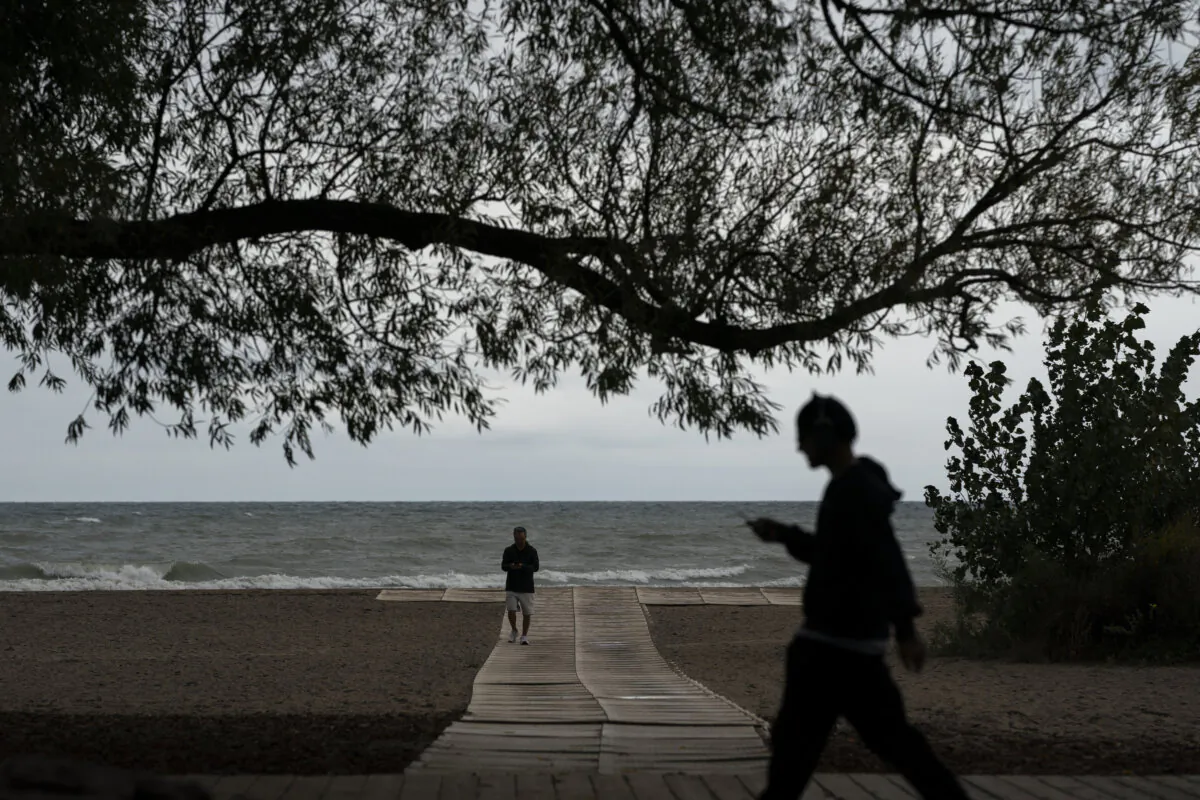 People walk by Lake Ontario's waterfront at Woodbine Park in Toronto on Sept. 24, 2024. (The Canadian Press/Paige Taylor White)