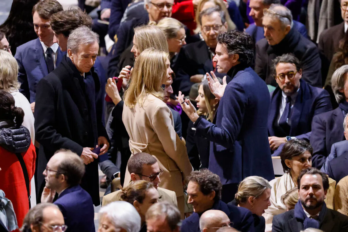 CEO of LVMH Bernard Arnault (L), Antoine Arnault, CEO of Berluti, center right, and members of the Arnault family talk in Notre Dame Cathedral before France's iconic cathedral is formally reopening its doors for the first time since a devastating fire nearly destroyed the 861-year-old landmark in 2019, in Paris, on Dec.7, 2024. (Ludovic Marin/Pool via AP)
