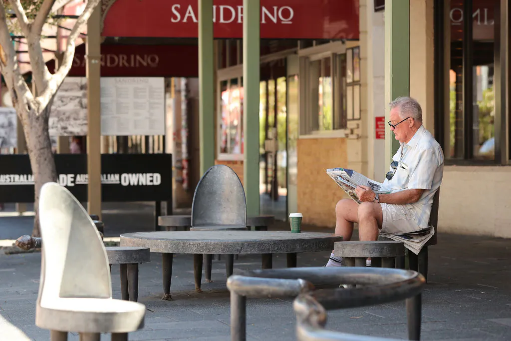 A man reads a local newspaper while sitting on roadside seating on South Terrace in Fremantle, Australia, on March 26, 2020. (Paul Kane/Getty Images)