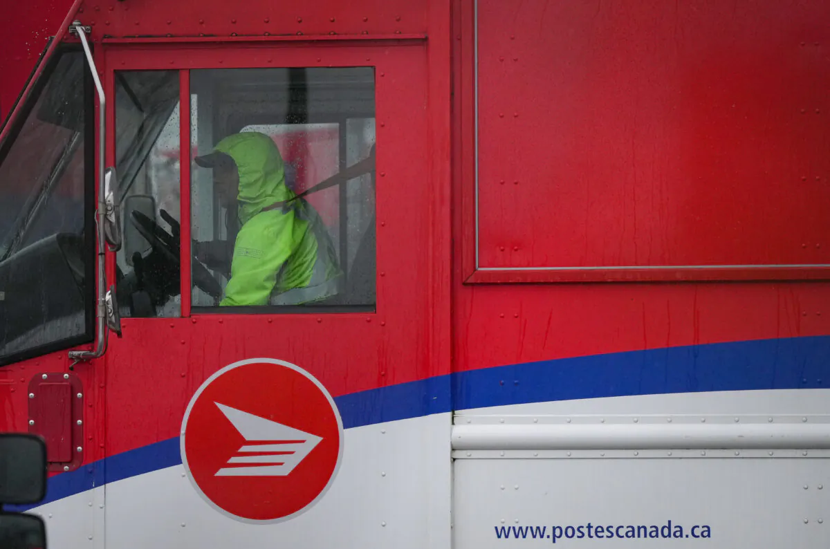 A Canada Post employee drives a mail truck at a delivery depot in Vancouver, on Dec. 17, 2024. (The Canadian Press/Darryl Dyck) 