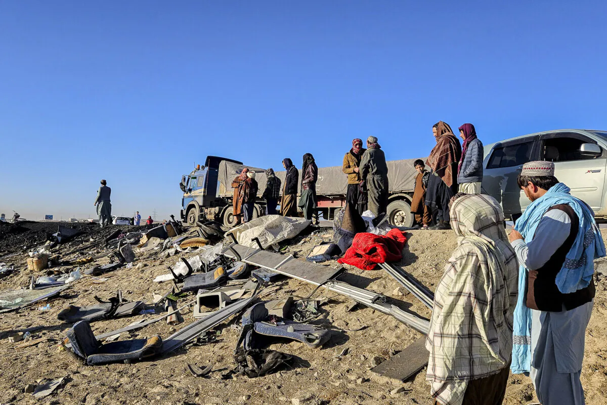 Afghan residents inspect the accident site as they stand near the remains of a bus following its collision with a coal truck on a highway, in the Andar district of Ghazni Province, on Dec. 19, 2024. (Mohammad Faisal Naweed/AFP via Getty Images)