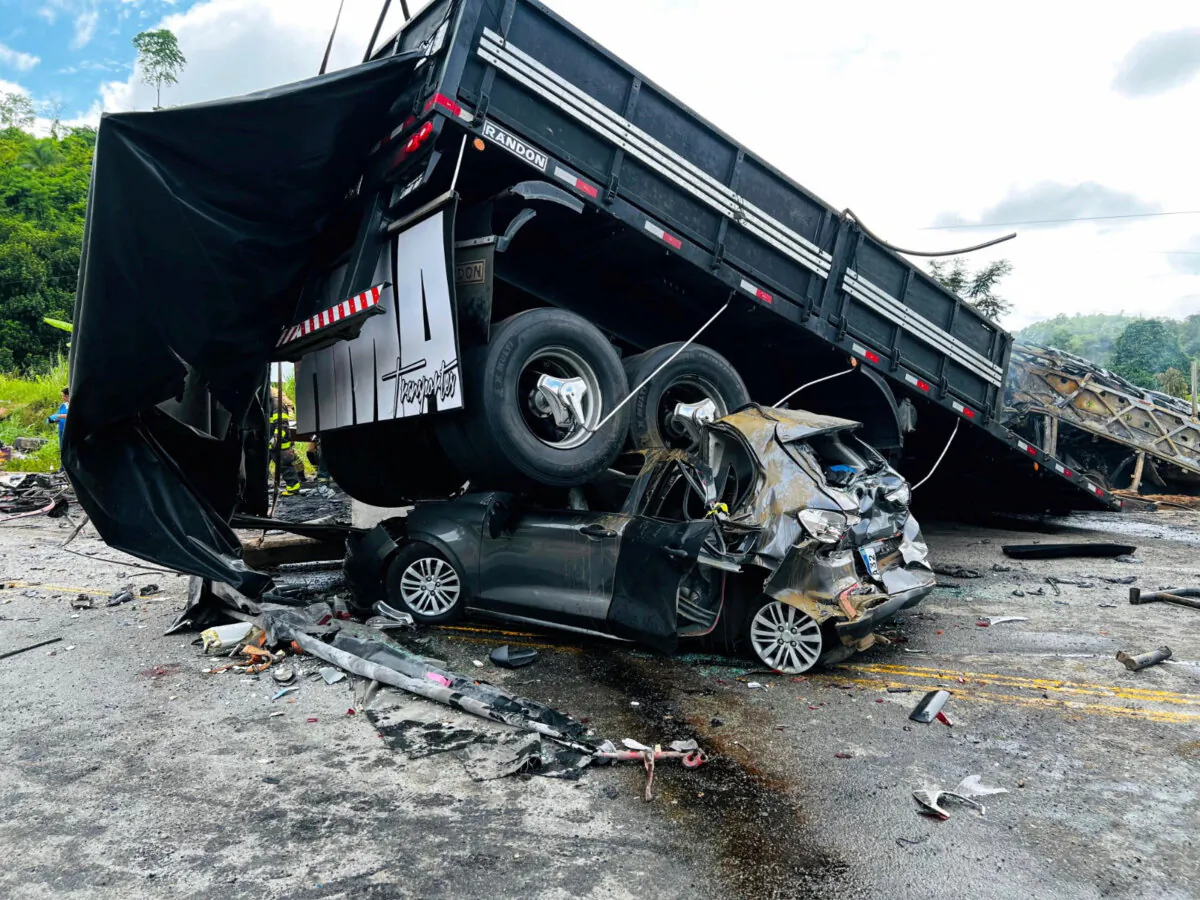 A damaged car is crushed under a vehicle following a traffic accident after a packed bus collided with a truck, at the Fernao Dias national highway, near Teofilo Otoni, Brazil, on Dec. 21, 2024. (Belo Horizonte Military Fire Department/­Handout via Reuters)