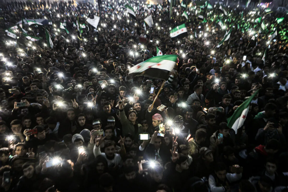 People gather with lit phones and wave independence-era Syrian flags during celebrations of the ouster of President Bashar al-Assad in the northwestern city of Idlib, Syria, on Dec. 22, 2024. (Aaref Watad/AFP via Getty Images)