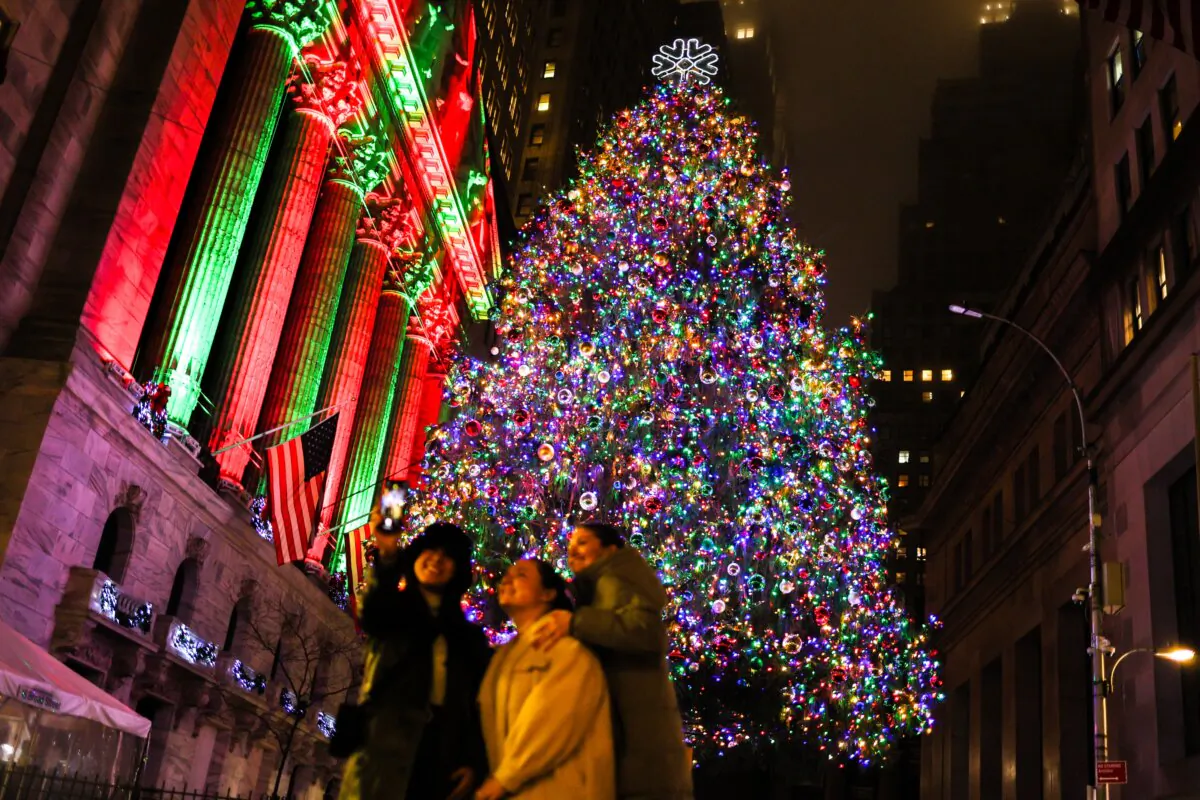 People take a selfie with the Christmas tree displayed outside the New York Stock Exchange on Dec. 16, 2024. (Charly Triballeau/AFP via Getty Images)