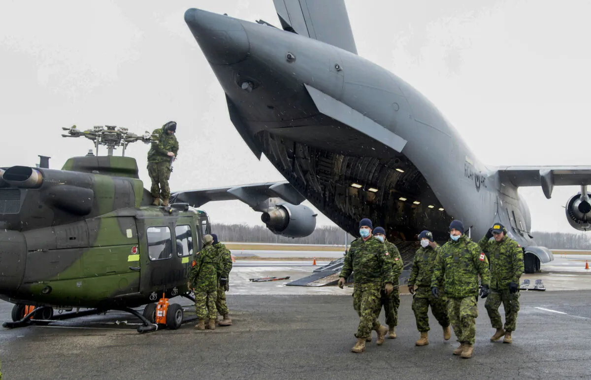Members of the Canadian Armed Forces prepare to load a helicopter onto a C-177 Globemaster III in Quebec City as part of sending relief to the flooded areas of British Columbia, on Nov. 19, 2021. (The Canadian Press/Jacques Boissinot)
