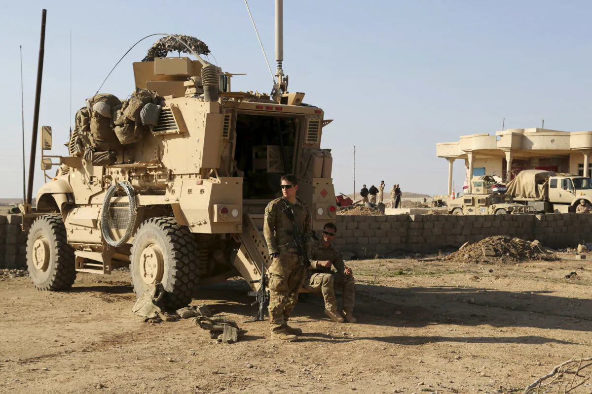 U.S. Army soldiers stand outside their armored vehicle on a joint base with the Iraqi army, south of Mosul, Iraq, on Feb. 23, 2017. (Khalid Mohammed/AP Photo)