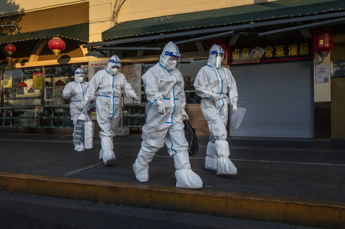 Pandemic control workers walk past a closed shop near a community with residents under health monitoring for COVID-19 in Beijing on Dec. 4, 2022. (Kevin Frayer/Getty Images)