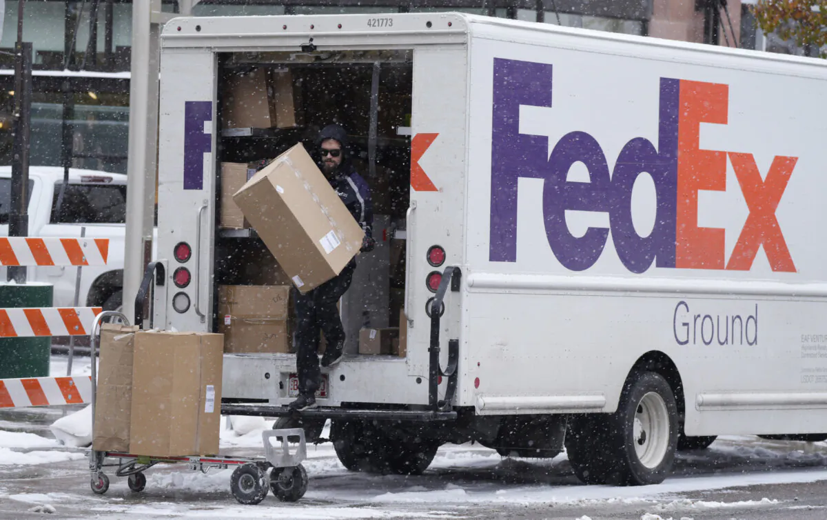 A FedEx delivery person carries a package from a truck in Denver, Co. (AP Photo/David Zalubowski, File)