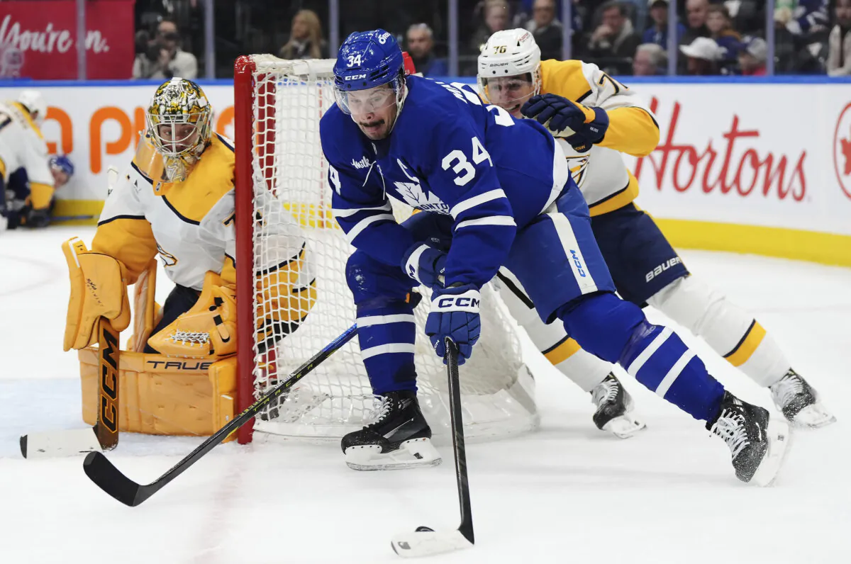 Toronto Maple Leafs' Auston Matthews (34) protects the puck from Nashville Predators' Brady Skjei (76) as goaltender Juuse Saros (74) looks on during the second period of an NHL hockey game in Toronto on Wednesday, Dec. 4, 2024. (Frank Gunn/The Canadian Press via AP)