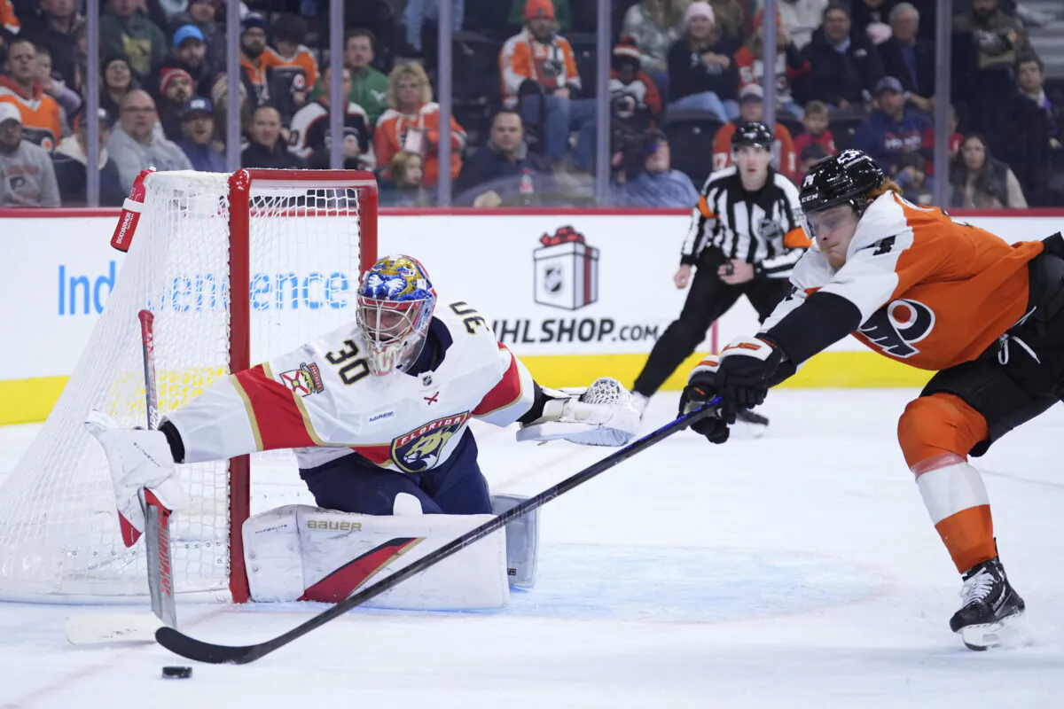 Philadelphia Flyers' Owen Tippett, right, and Florida Panthers' Spencer Knight reach for the puck during the second period of an NHL hockey game, Thursday, Dec. 5, 2024, in Philadelphia. (Matt Slocum/AP Photo)