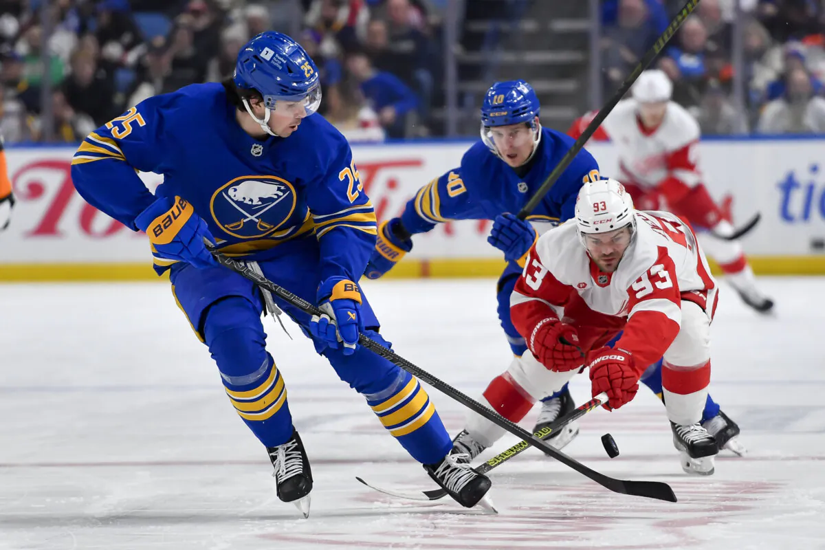 Detroit Red Wings right wing Alex DeBrincat, right, reaches for the puck against Buffalo Sabres defenseman Owen Power during the first period of an NHL hockey game in Buffalo, N.Y., on Dec. 9, 2024. (Adrian Kraus/AP Photo)
