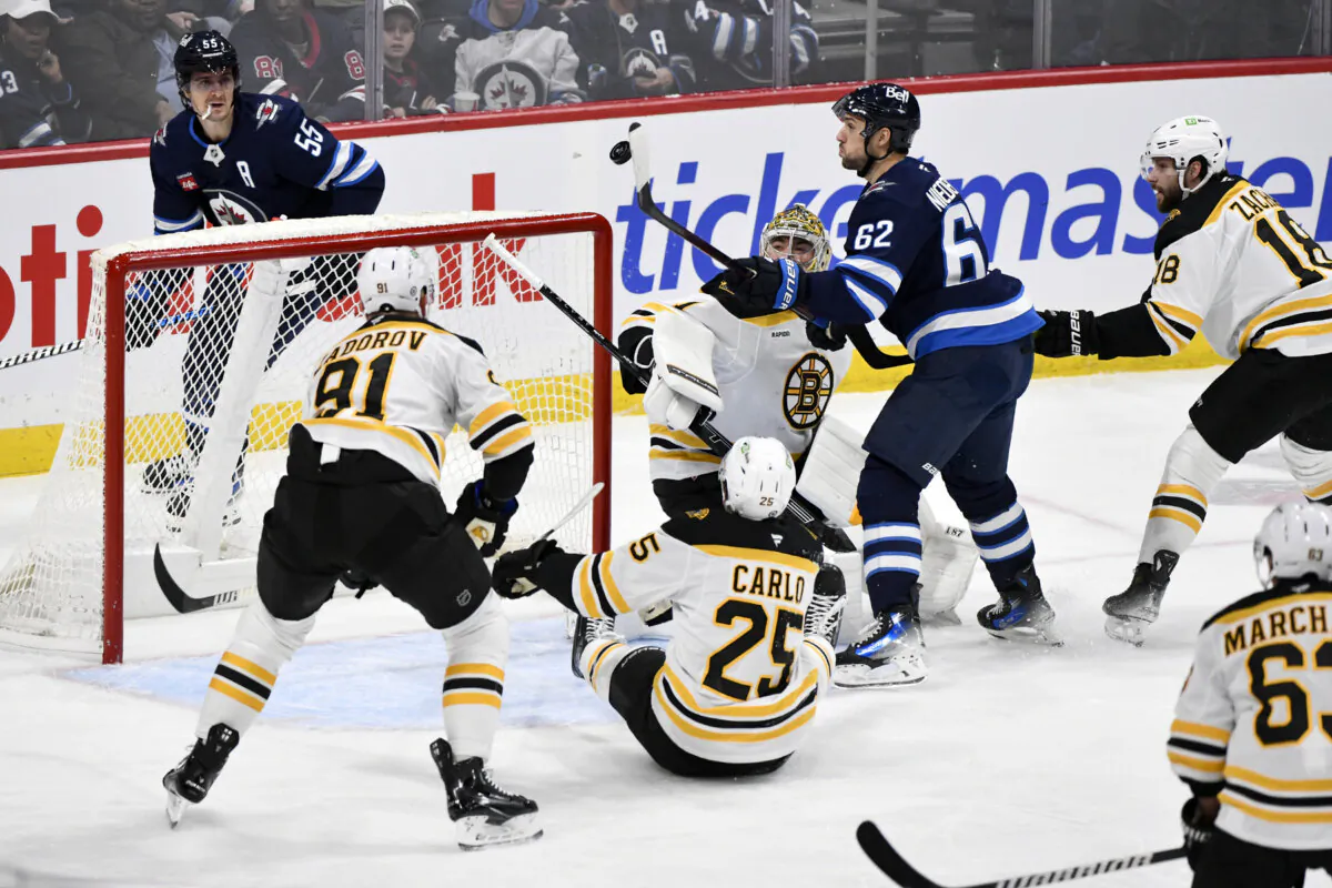 Winnipeg Jets' Nino Niederreiter reaches for a bouncing puck in front of Boston Bruins goaltender Jeremy Swayman during the first period of an NHL hockey game in Winnipeg, Manitoba, on Dec. 10, 2024. (Fred Greenslade/The Canadian Press via AP)