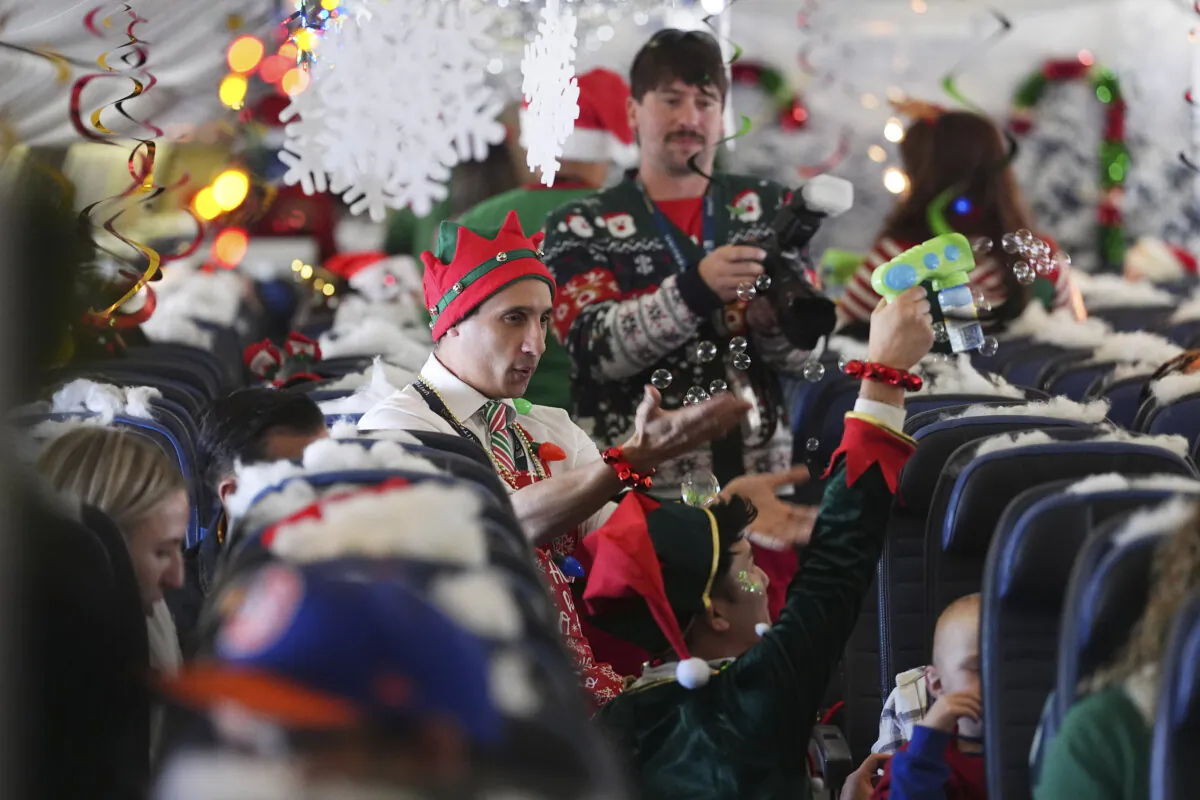Flight attendant Gustavo Oliveira (C) juggles bubbles to entertain passengers during the United Airlines annual "fantasy flight" to a fictional North Pole at Denver International Airpor in Denver on Dec. 14, 2024. (David Zalubowski/AP Photo)