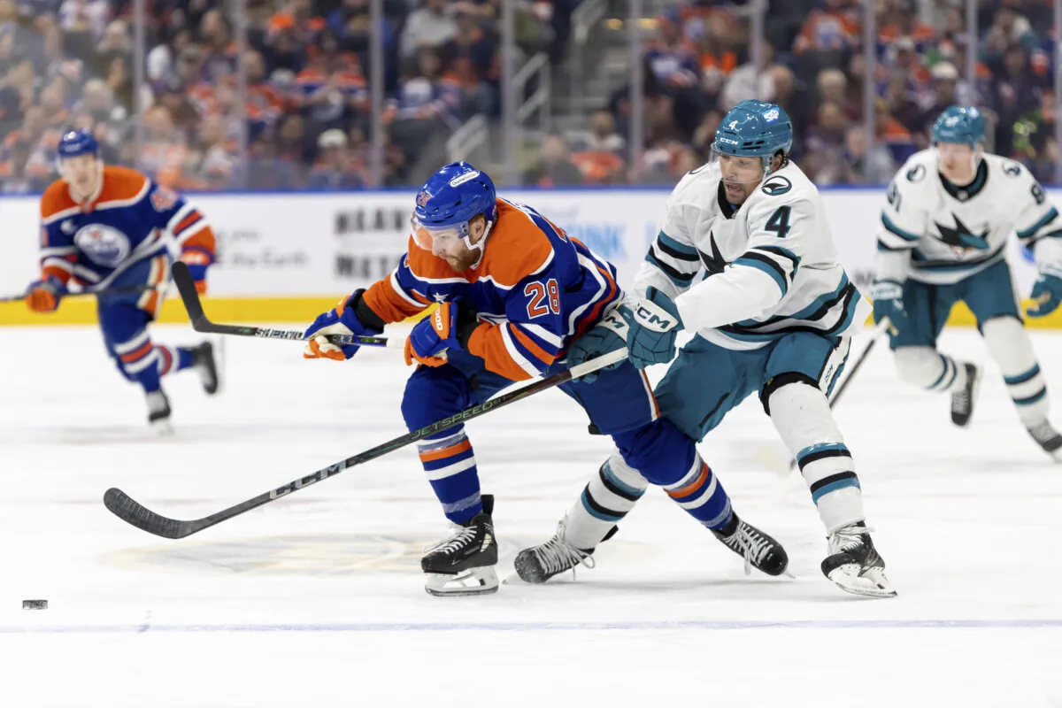 Edmonton Oilers' Connor Brown (28) battles for the puck against San Jose Sharks' Cody Ceci (4) during the second period of an NHL hockey game in Edmonton, Alberta, Saturday, Dec. 21, 2024. (Timothy Matwey/The Canadian Press via AP)