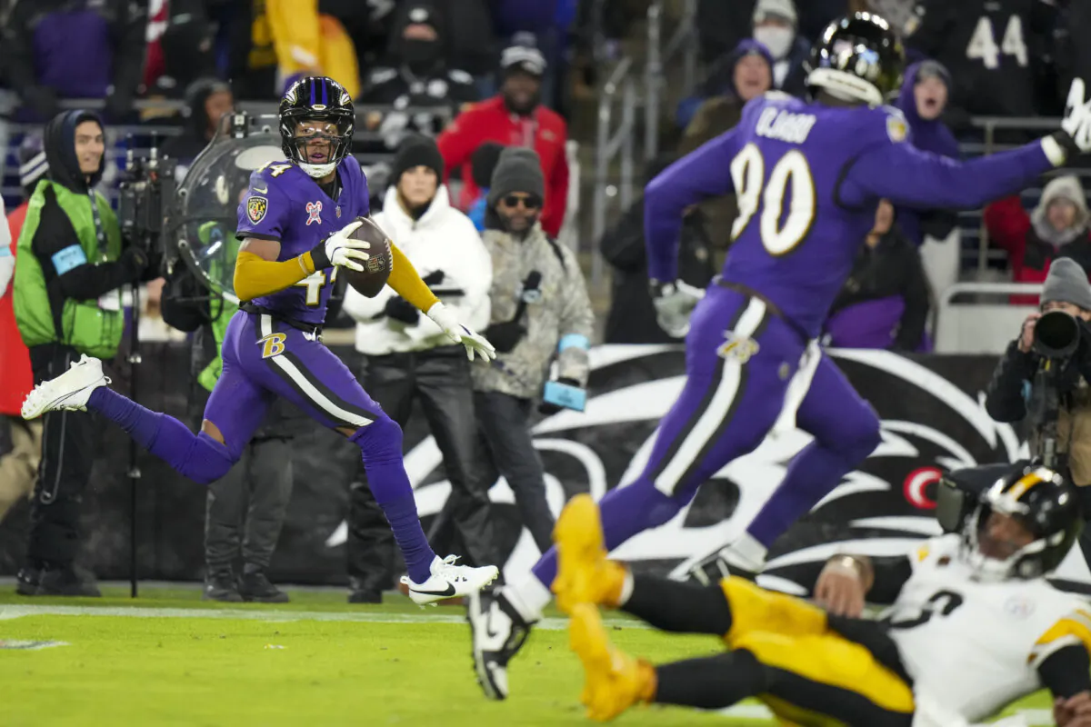 Pittsburgh Steelers quarterback Russell Wilson, bottom right, hits the turf as Baltimore Ravens cornerback Marlon Humphrey, left, returns an interception for a touchdown during the second half of an NFL football game, Saturday, Dec. 21, 2024, in Baltimore. (Stephanie Scarbrough/AP Photo)