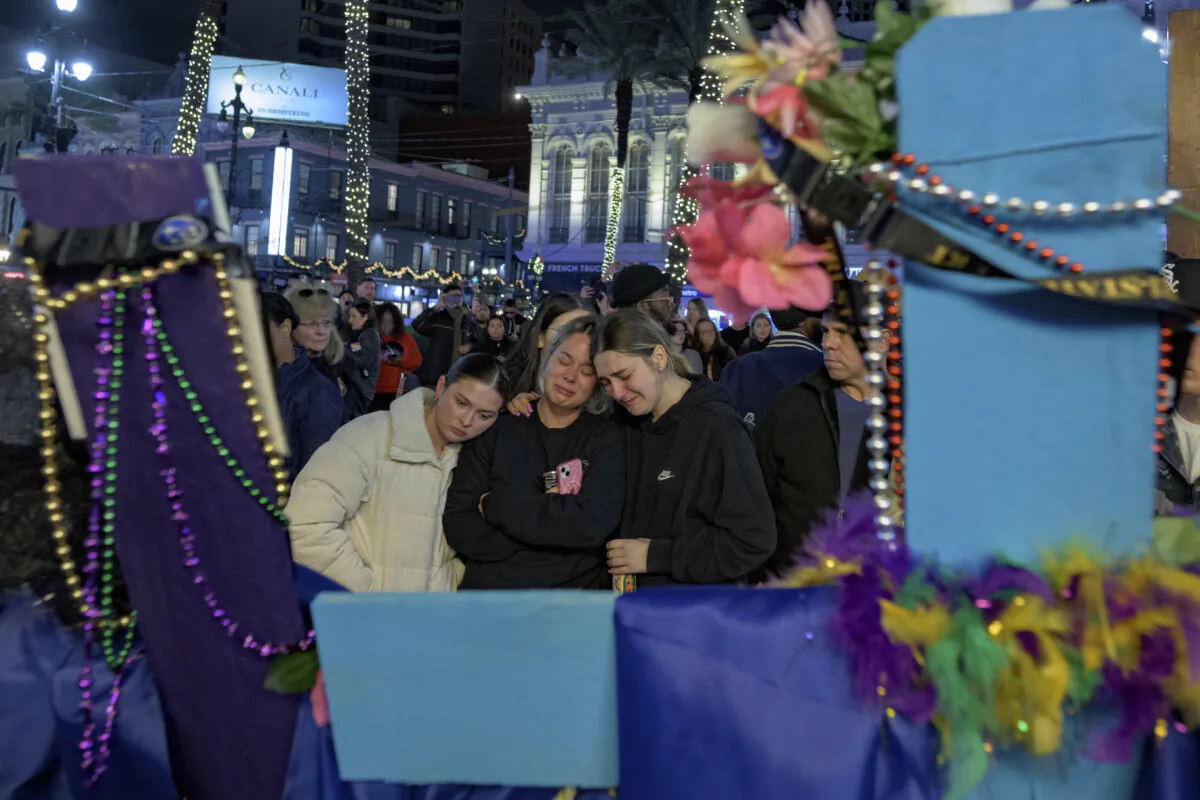 Mourners react next to crosses memorializing the victims of the New Year's Day deadly truck attack and shooting along Canal Street near the intersection of Bourbon Street in New Orleans, on Jan. 4, 2025. (The Associated Press/Matthew Hinton)
