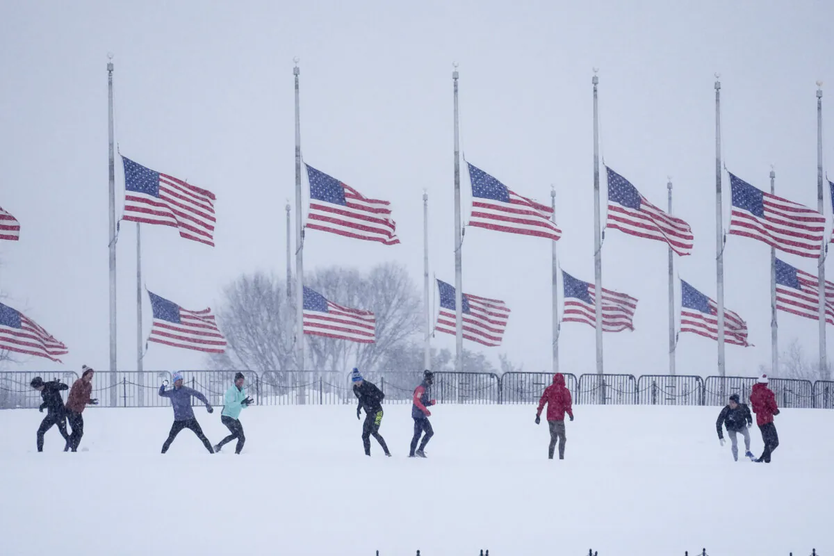 People engage in a snowball fight as U.S. flags, along the base of the Washington Monument, fly at half-mast in remembrance of President Jimmy Carter, in Washington, on Jan. 6, 2025. (Matt Rourke/AP Photo)