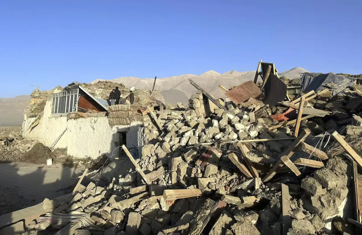 People stand amidst damaged houses in the aftermath of an earthquake in Tonglai Village, Changsuo Township of Dingri in Xigaze, Tibet, on Jan. 7, 2025. (Xinhua via AP)