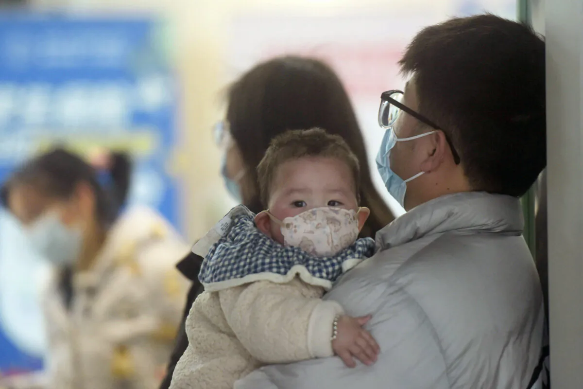 A baby wearing a face mask waits with family members at the pediatric department of a hospital in Hangzhou, eastern Zhejiang Province, China, on Jan. 6, 2025. (STR/AFP via Getty Images)