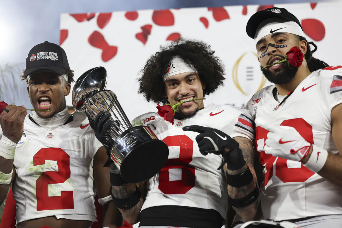Emeka Egbuka No. 2, Lathan Ransom No. 8, and Gee Scott Jr. No. 88 of the Ohio State Buckeyes celebrate with the Leishman Trophy after defeating the Oregon Ducks 41–21 in the Rose Bowl Game Presented by Prudential at Rose Bowl Stadium  in Pasadena, Calif., on Jan. 1, 2025. (Harry How/Getty Images)