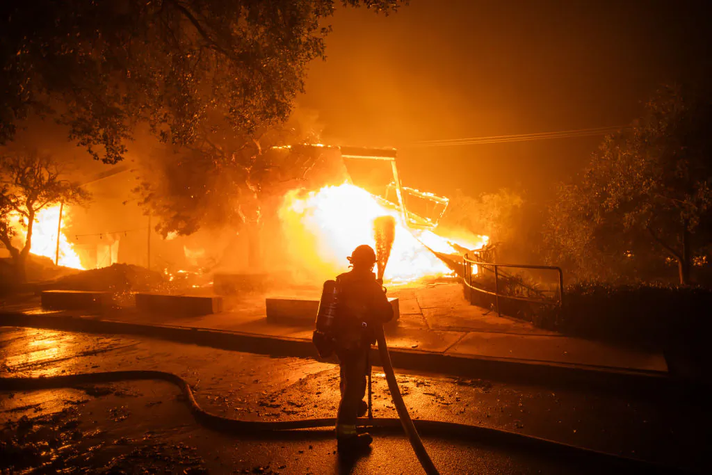 A firefighter fights the flames from the Palisades Fire burning the Theatre Palisades during a powerful windstorm in the Pacific Palisades neighborhood of Los Angeles, Calif., on Jan. 8, 2025. (Apu Gomes/Getty Images)