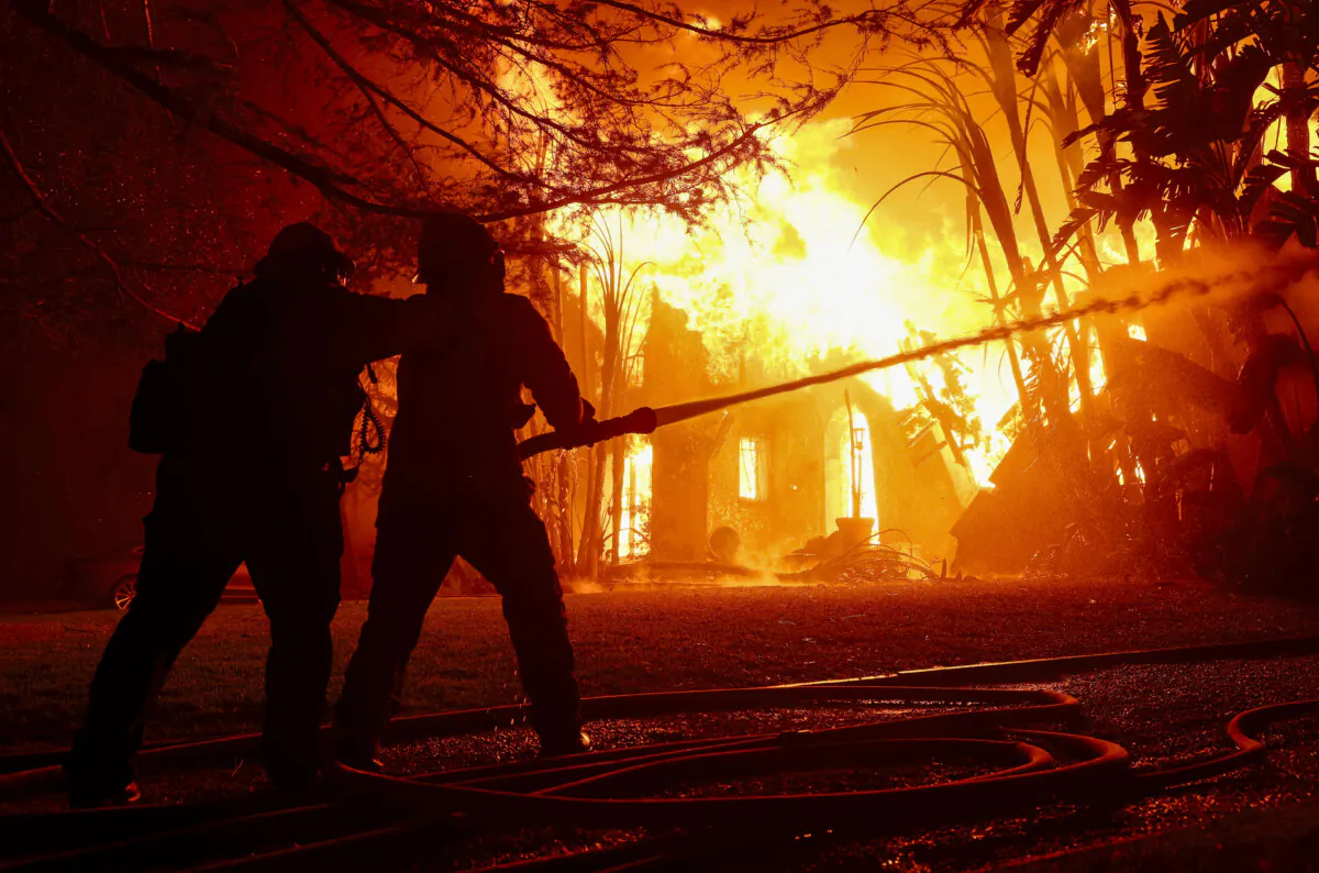 Los Angeles County firefighters spray water on a burning home as the Eaton Fire moves through the area in Altadena, Calif., on Jan. 8, 2025. (Justin Sullivan/Getty Images)