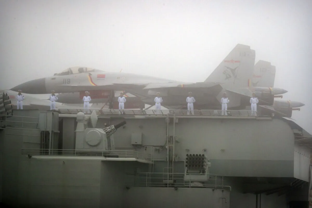 Sailors stand near fighter jets on the deck of the Chinese People's Liberation Army Navy aircraft carrier Liaoning as it participates in a naval parade to commemorate the 70th anniversary of the founding of China's PLA Navy in the sea near Qingdao, in eastern China's Shandong Province, on April 23, 2019. (Mark Schiefelbein/AFP via Getty Images)