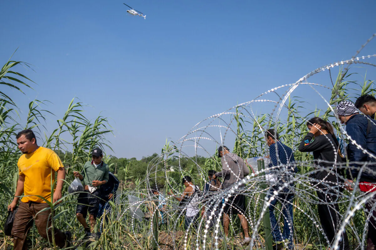 Illegal immigrants from El Salvador walk through brush alongside the banks of the Rio Grande after crossing into the United States in Eagle Pass, Texas, on May 21, 2022. (Brandon Bell/Getty Images)