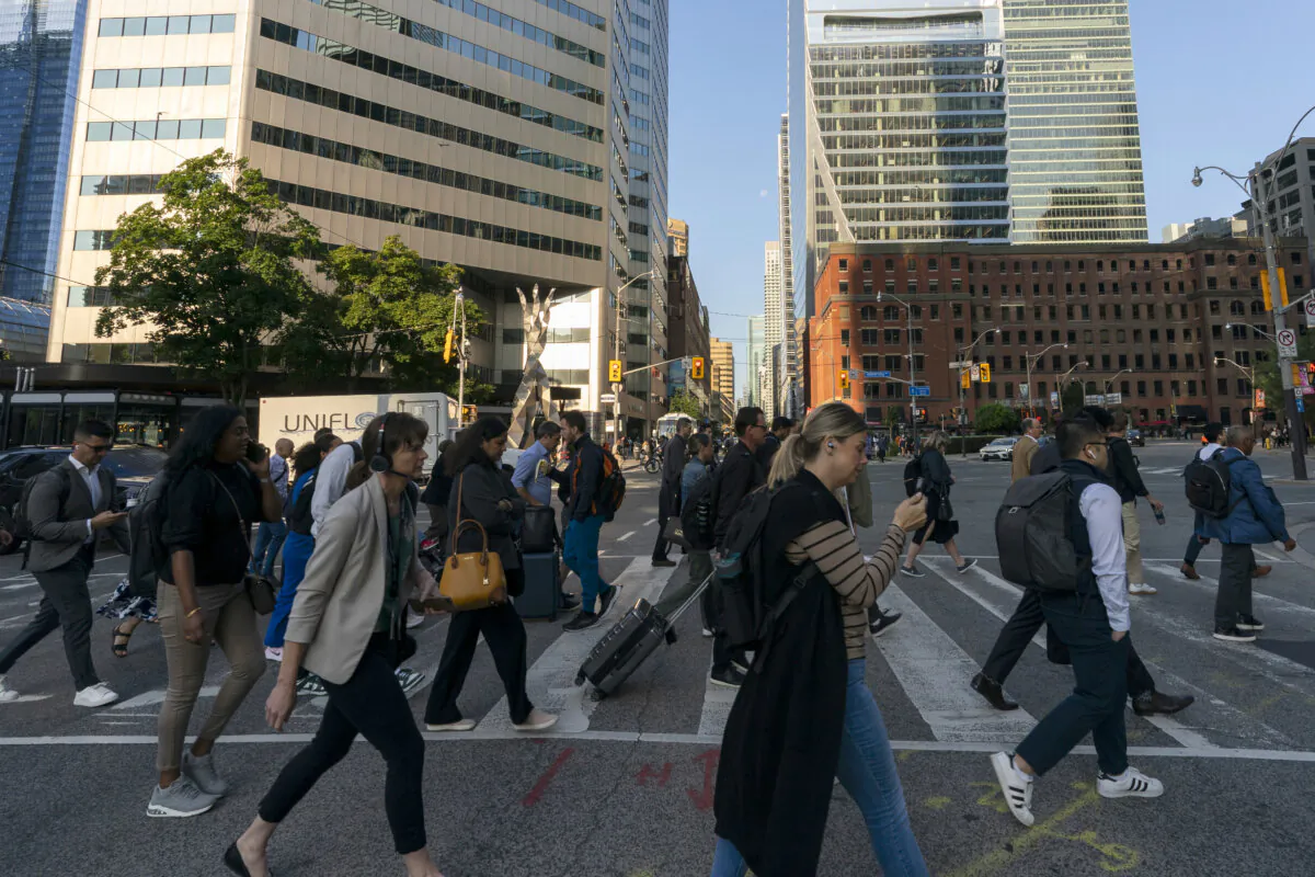 People cross a street in downtown Toronto during the morning commute on Aug. 22, 2024. (The Canadian Press/Paige Taylor White)