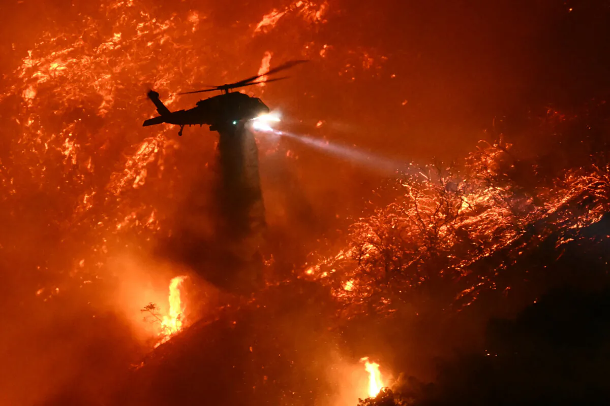 A firefighting helicopter drops water as the Palisades fire grows near the Mandeville Canyon neighborhood and Encino, Calif., on Jan. 11, 2025. (Patrick T. Fallon/AFP via Getty Images)