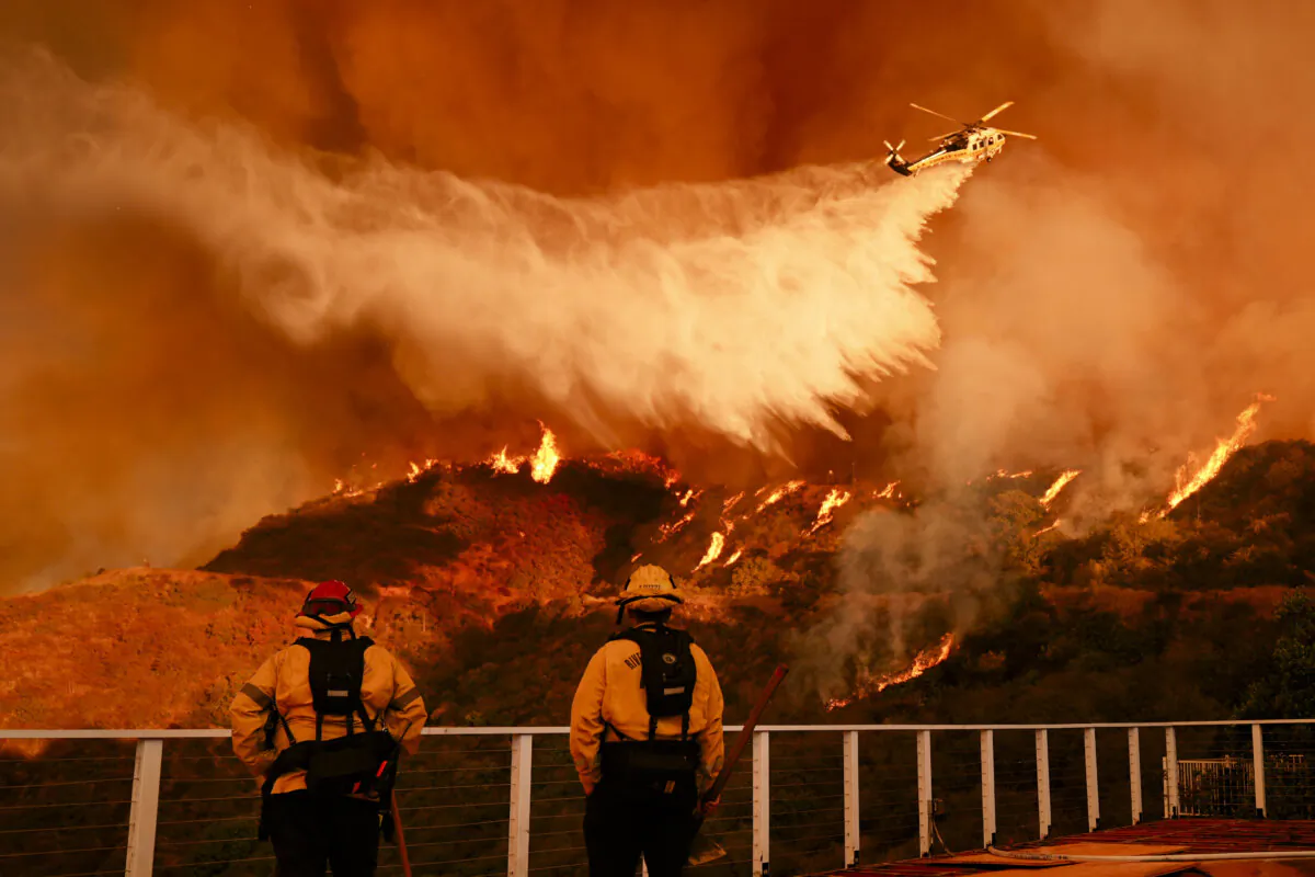 Firefighters watch as water is dropped on the Palisades Fire in Mandeville Canyon in Los Angeles, on Jan. 11, 2025. (Jae C. Hong/AP Photo)