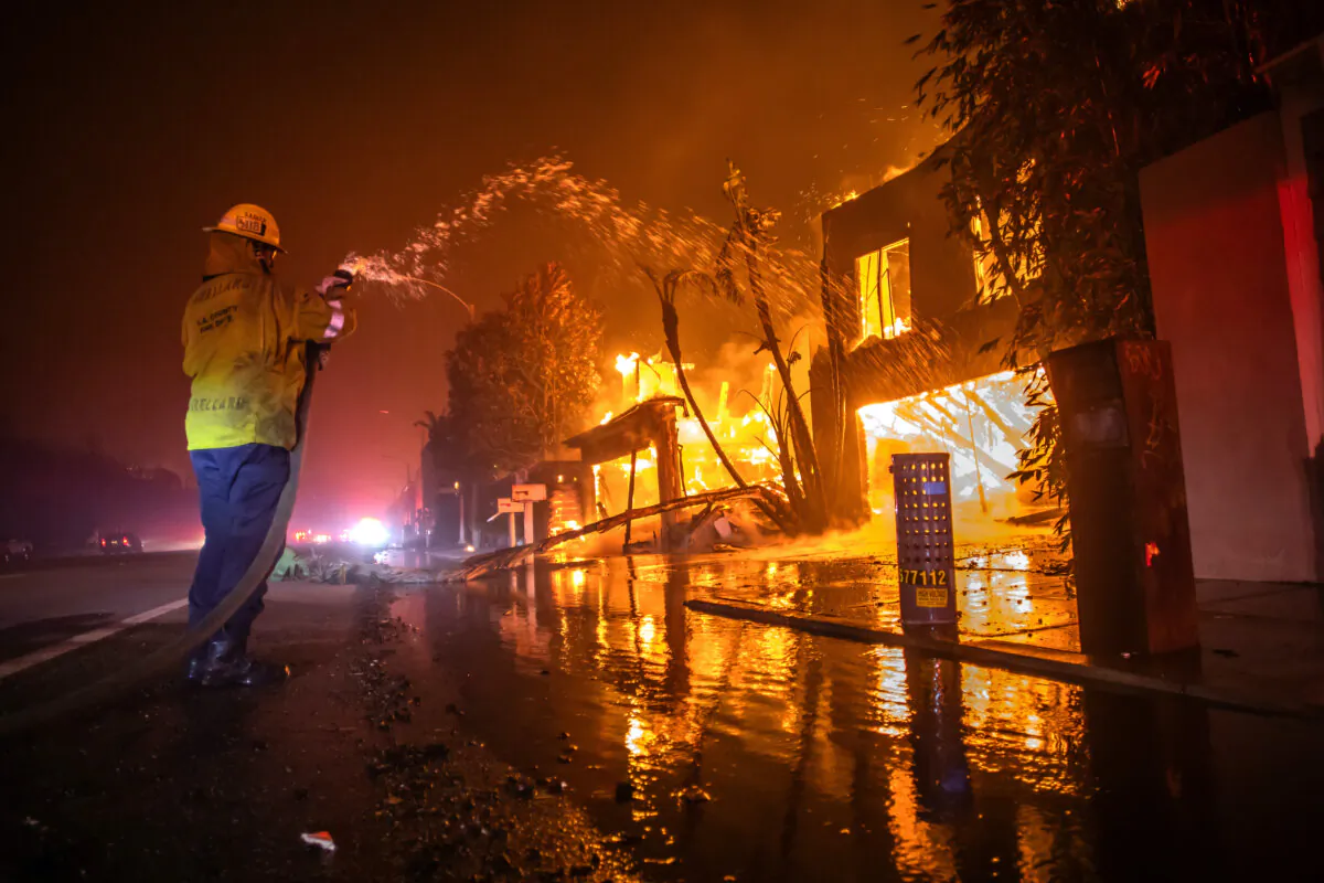 A firefighter fights the flames from the Palisades Fire while it burns homes at Pacific Coast Highway amid a powerful windstorm in Malibu, Calif., on Jan. 8, 2025. (Apu Gomes/Getty Images)