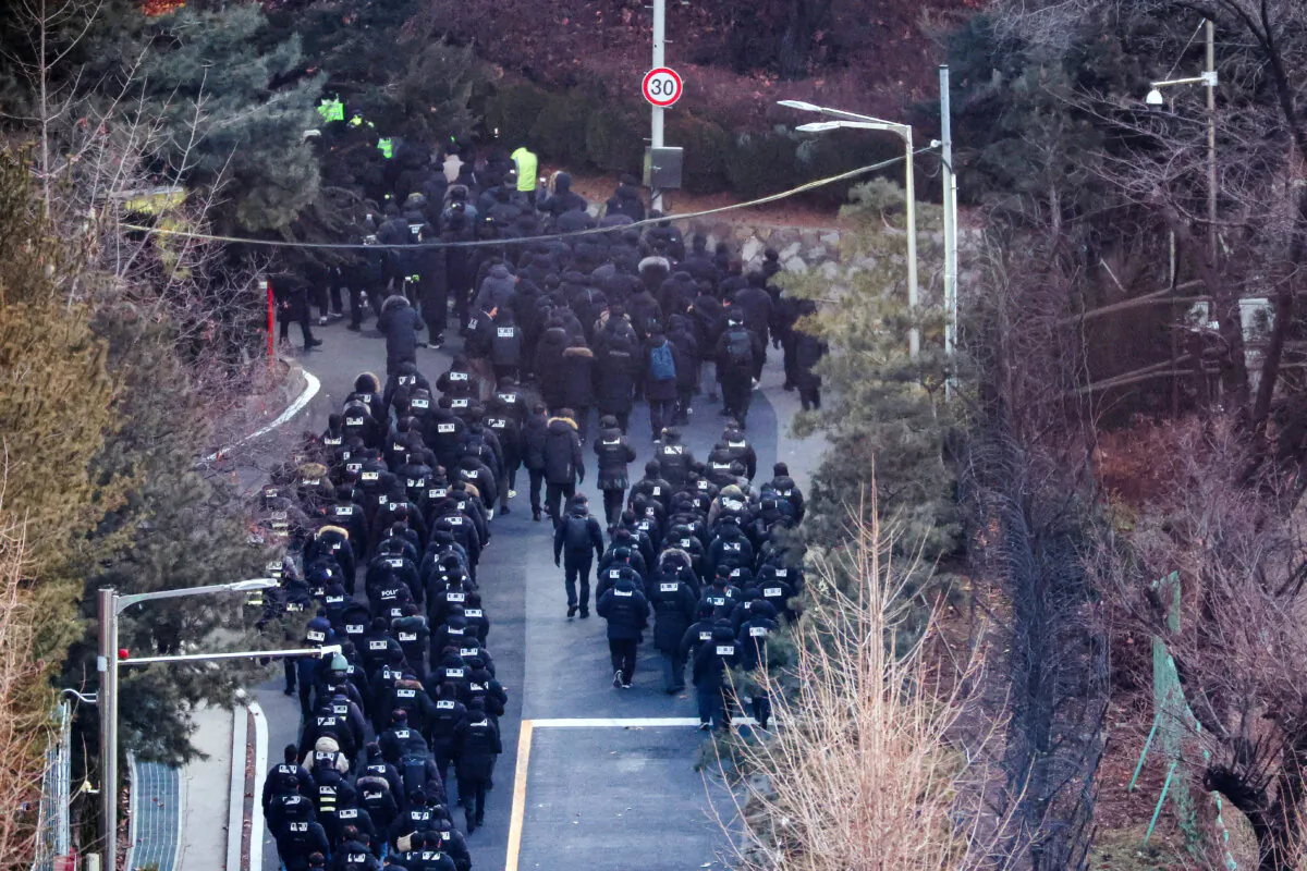 Police officers and investigators of the Corruption Investigation Office for High-ranking Officials pass through the entrance to the official residence of impeached South Korean President Yoon Suk Yeol, as authorities are seeking to execute an arrest warrant, in Seoul, South Korea, on Jan. 15, 2025. (Kim Hong-Ji/Reuters)